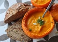 Creamy pumpkin soup and homemade bread on grey tiled table. Soup in a squash top view photo. Thanksgiving menu ideas.ÃÂ ÃÂ  Royalty Free Stock Photo